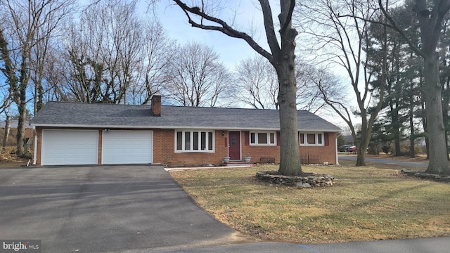 ranch-style house featuring a garage, driveway, brick siding, a chimney, and a front yard