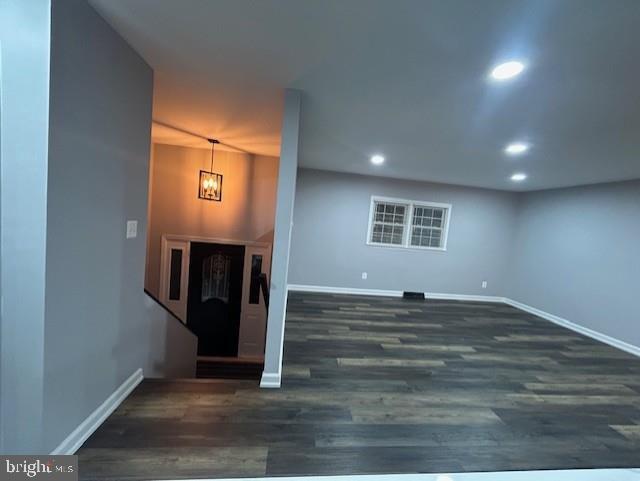 unfurnished living room featuring a chandelier and dark hardwood / wood-style floors