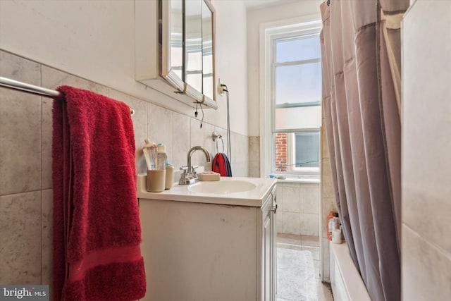 bathroom with shower / bath combo, vanity, and tile walls