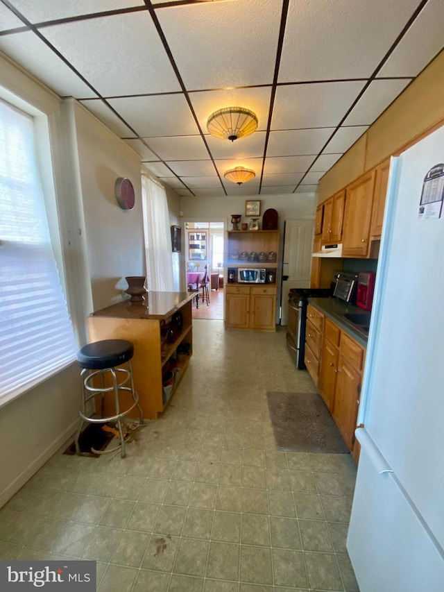 kitchen with appliances with stainless steel finishes, a breakfast bar, and a drop ceiling