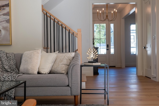 living room with a wealth of natural light, wood-type flooring, and a notable chandelier