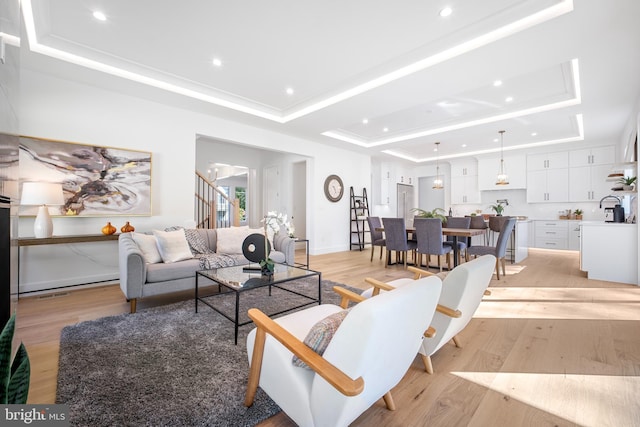 living room with a raised ceiling and light wood-type flooring