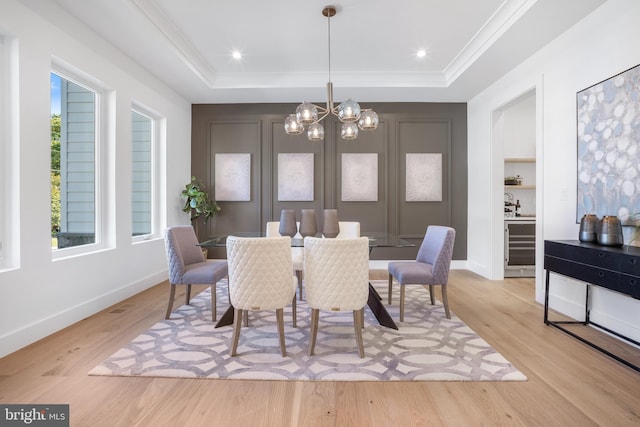 dining space with a notable chandelier, plenty of natural light, and a tray ceiling