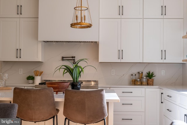 kitchen featuring white cabinets, backsplash, and hanging light fixtures