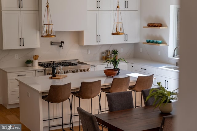 kitchen featuring decorative backsplash, white cabinetry, sink, and pendant lighting