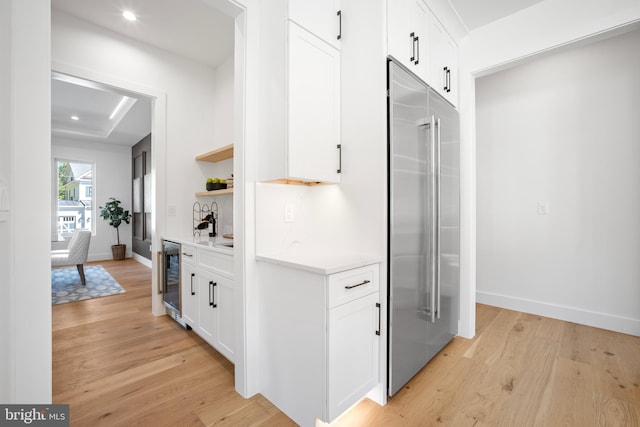 kitchen featuring wine cooler, white cabinetry, built in refrigerator, and light hardwood / wood-style floors