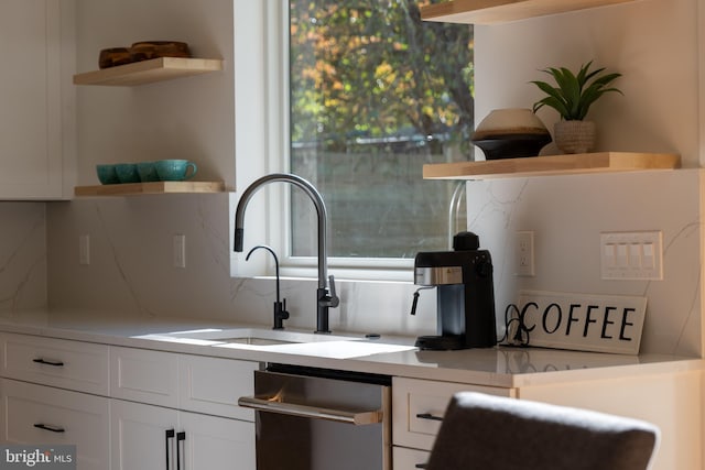 kitchen with dishwasher, backsplash, white cabinetry, and sink