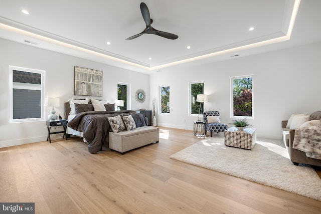 bedroom with a tray ceiling, light hardwood / wood-style flooring, and ceiling fan