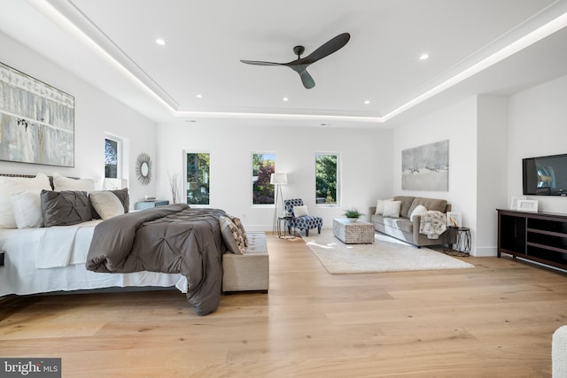 bedroom with a raised ceiling, ceiling fan, and light hardwood / wood-style flooring