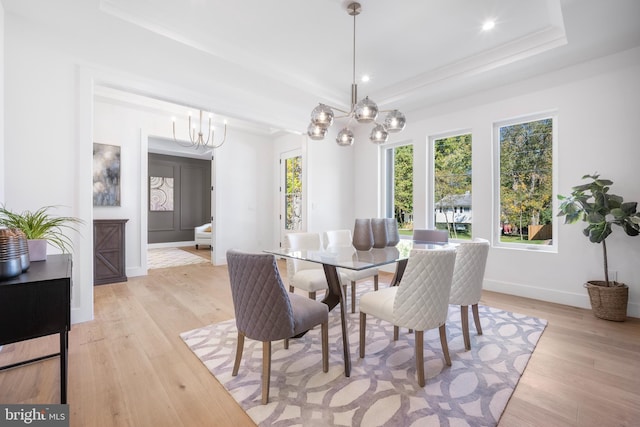 dining space featuring a notable chandelier, light hardwood / wood-style floors, and a tray ceiling