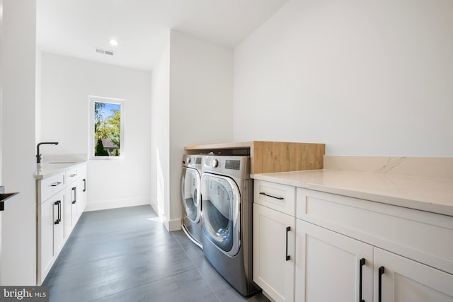 clothes washing area featuring washing machine and clothes dryer, sink, and cabinets