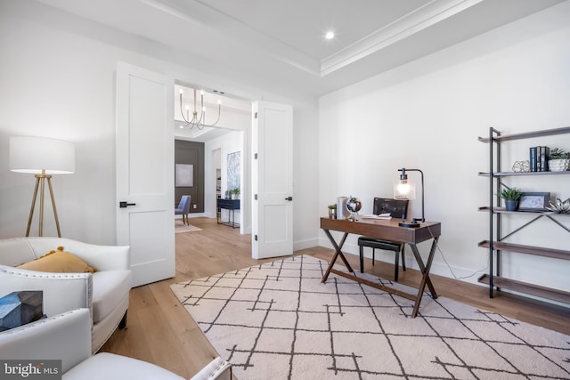 office featuring light wood-type flooring, a tray ceiling, crown molding, and a notable chandelier