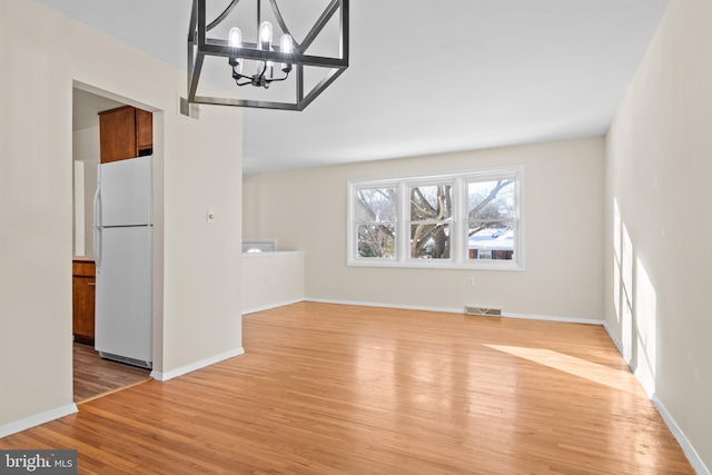 unfurnished dining area featuring a chandelier and light hardwood / wood-style floors