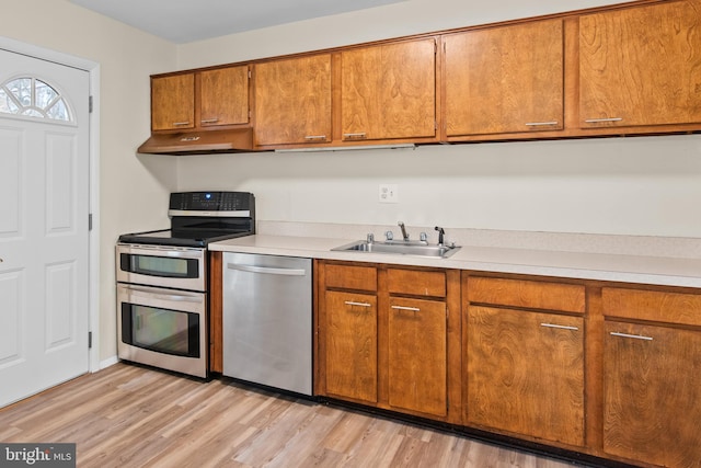 kitchen with sink, stainless steel appliances, and light hardwood / wood-style floors