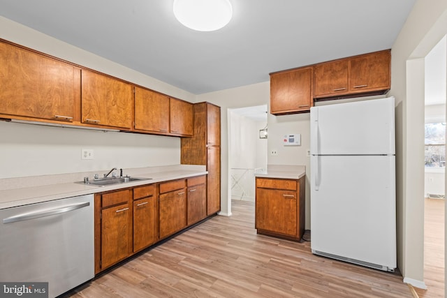 kitchen with white refrigerator, light hardwood / wood-style flooring, stainless steel dishwasher, and sink