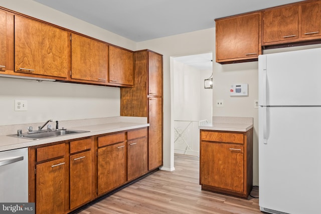 kitchen featuring stainless steel dishwasher, white refrigerator, sink, and light hardwood / wood-style flooring