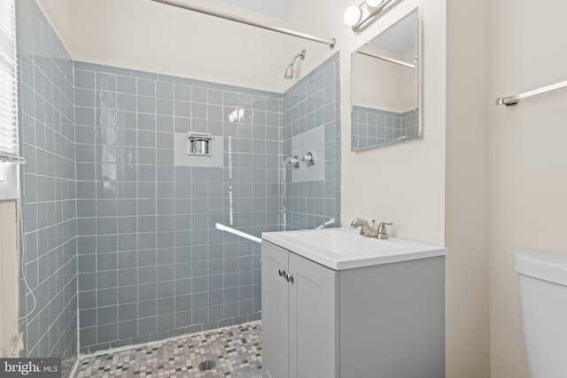 bathroom featuring tiled shower, vanity, and toilet