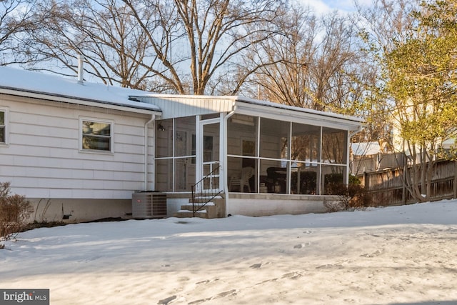 snow covered house with a sunroom and central air condition unit