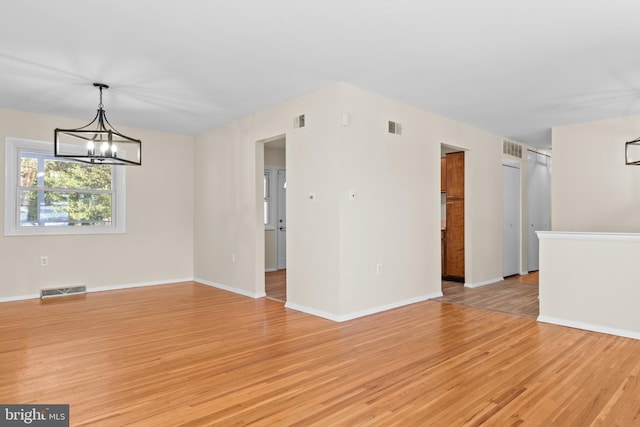 unfurnished room featuring a chandelier and light hardwood / wood-style floors