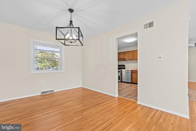 unfurnished dining area featuring light hardwood / wood-style flooring and an inviting chandelier