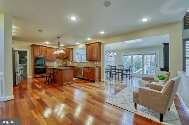 kitchen featuring tasteful backsplash, a breakfast bar, stainless steel appliances, a center island, and hanging light fixtures