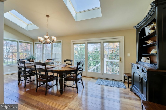 dining room featuring a chandelier, wood-type flooring, and vaulted ceiling with skylight