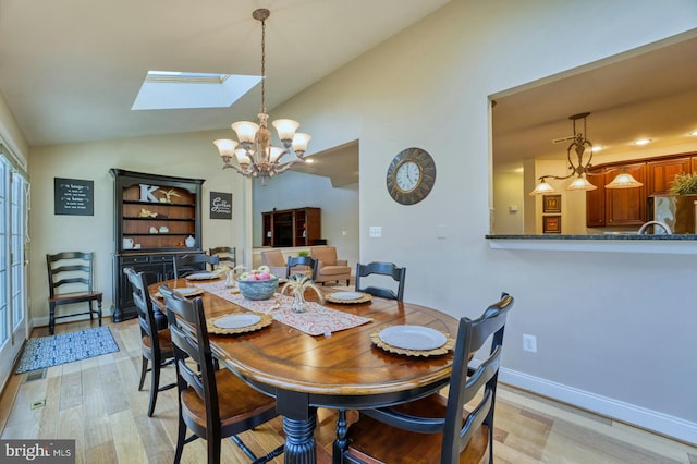 dining room featuring an inviting chandelier, lofted ceiling with skylight, and light hardwood / wood-style flooring