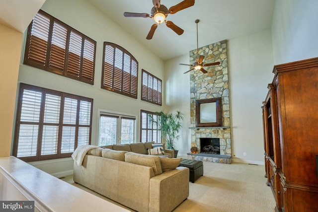 living room featuring ceiling fan, a fireplace, high vaulted ceiling, and light colored carpet