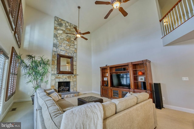 carpeted living room with high vaulted ceiling, ceiling fan, and a stone fireplace