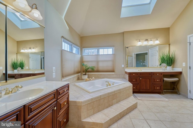 bathroom with tile patterned floors, tiled bath, lofted ceiling with skylight, and vanity