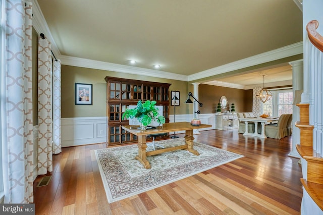 dining room with decorative columns, crown molding, hardwood / wood-style floors, and an inviting chandelier