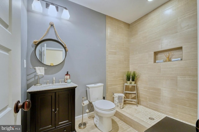 bathroom featuring tiled shower, vanity, and toilet