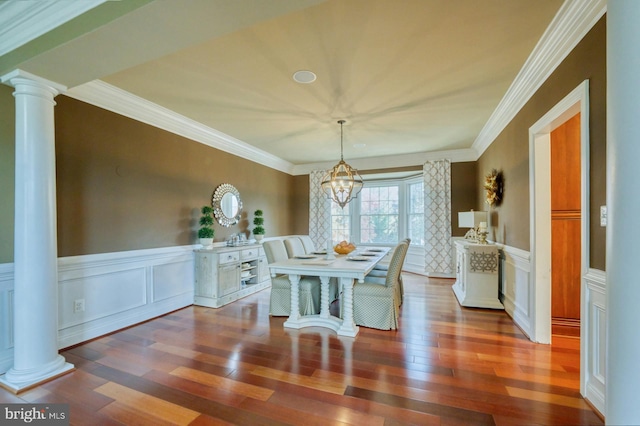 dining room with ornate columns, dark hardwood / wood-style flooring, ornamental molding, and an inviting chandelier