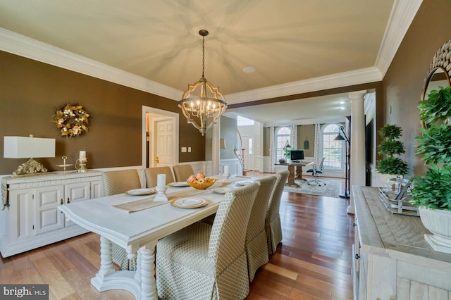 dining room with decorative columns, light hardwood / wood-style flooring, ornamental molding, and a notable chandelier