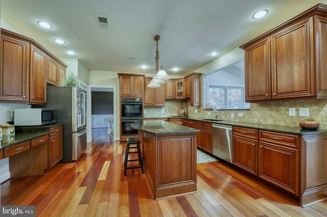 kitchen with a kitchen breakfast bar, a kitchen island, appliances with stainless steel finishes, and dark stone counters