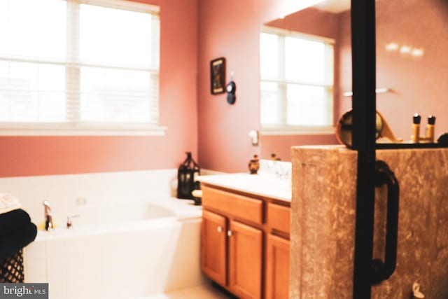 bathroom with plenty of natural light, a bath, and vanity