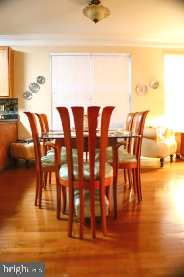 dining space featuring ornamental molding and light hardwood / wood-style flooring