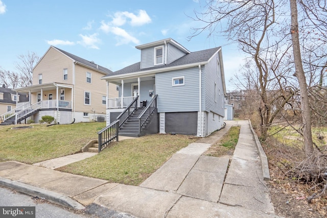 bungalow with a front lawn, stairway, covered porch, and driveway