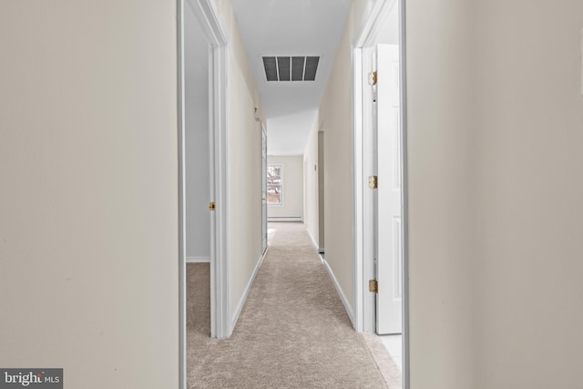 corridor with a baseboard radiator and light carpet