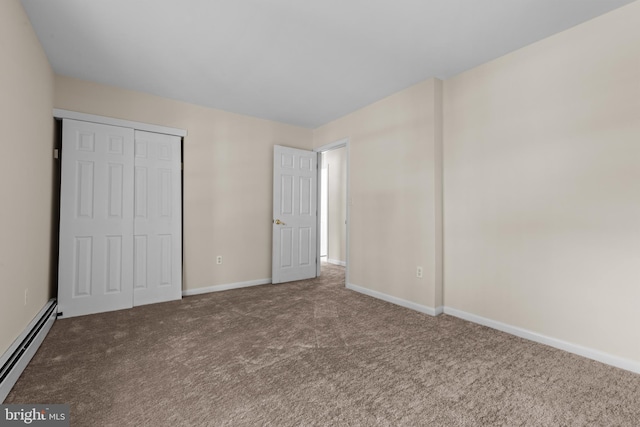 unfurnished bedroom featuring a baseboard heating unit, a closet, and carpet flooring