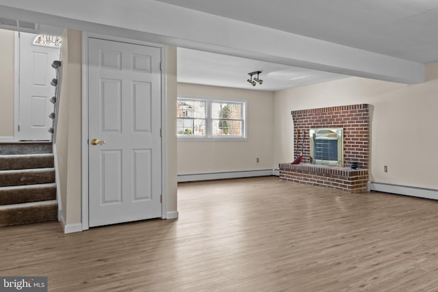 unfurnished living room featuring baseboard heating, a fireplace, and light hardwood / wood-style floors