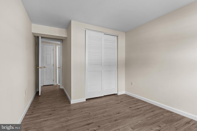 unfurnished bedroom with dark wood-type flooring and a closet