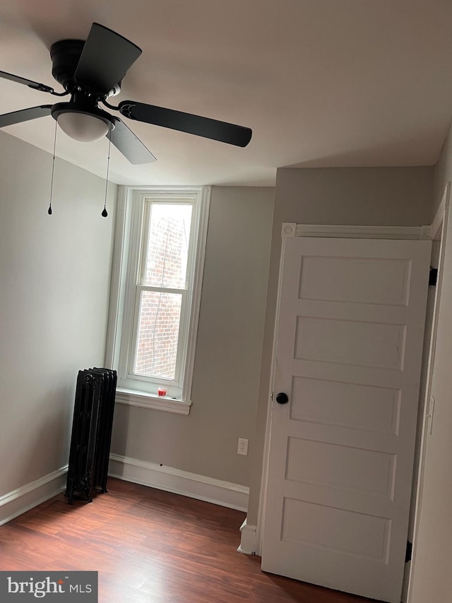 unfurnished bedroom with radiator, ceiling fan, and wood-type flooring