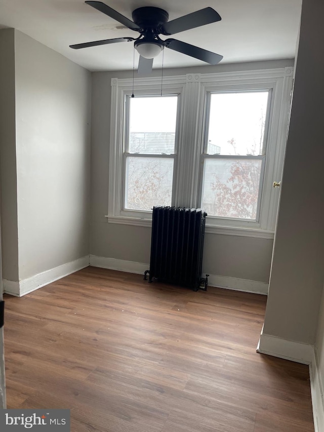 unfurnished room featuring ceiling fan, radiator heating unit, and wood-type flooring