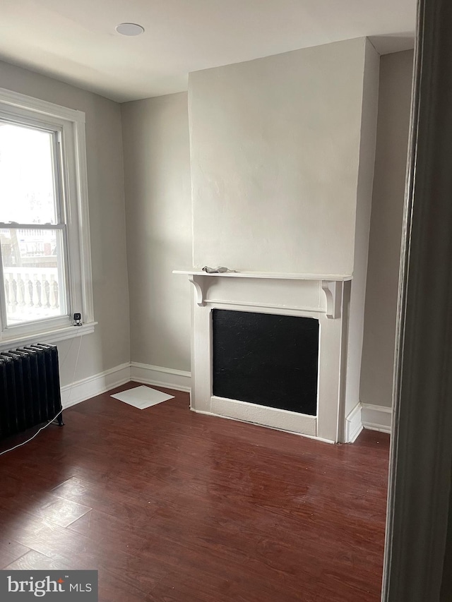 unfurnished living room with radiator heating unit and dark wood-type flooring