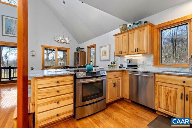 kitchen featuring sink, tasteful backsplash, light hardwood / wood-style floors, a chandelier, and appliances with stainless steel finishes