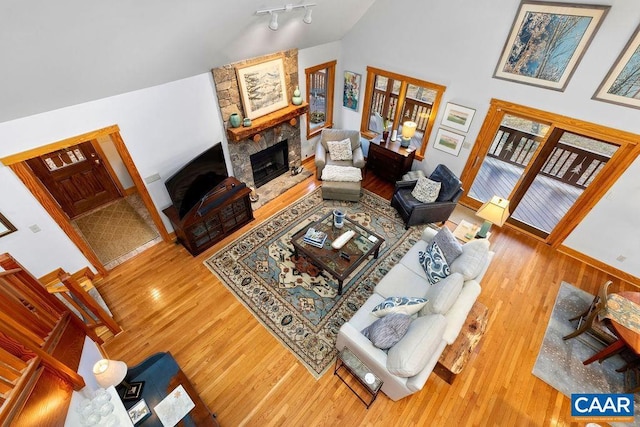 living room with a stone fireplace, a high ceiling, and hardwood / wood-style flooring