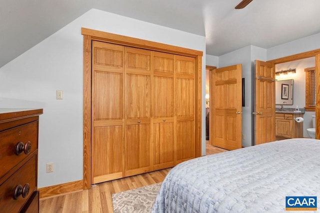 bedroom with light wood-type flooring, ensuite bath, ceiling fan, sink, and a closet