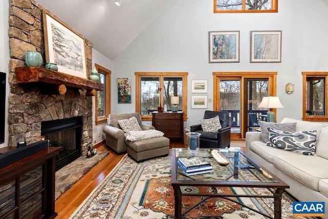 living room with light hardwood / wood-style floors, a fireplace, and high vaulted ceiling