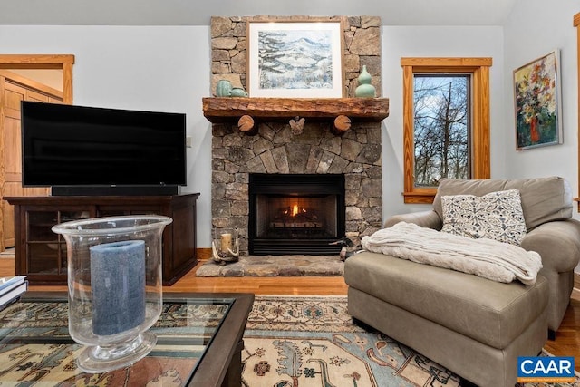 living room featuring a stone fireplace and hardwood / wood-style flooring